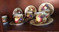 Six demitasse cups and saucers arranged on shelf showing full set and pattern