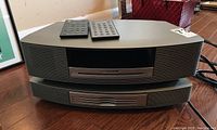 Front view of Bose Wave Music System stacked with 4-disc changer and two remotes on top
