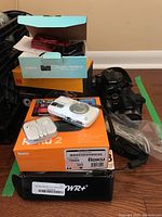 Overview of all items stacked: printer dock box, cameras, boxes and adapters