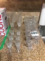 Photo showing various crystal glasses arranged on a countertop including liquor glasses with cross patterns, champagne flutes, and others.