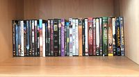 DVD collection arranged on wooden shelving, approximately 35 DVDs including TV series and movies