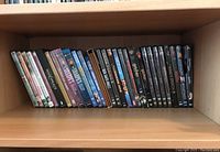 Shelf with approximately 30 DVD cases showing titles including War & Peace and Harry Potter DVDs