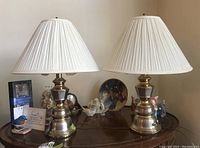 Two matching table lamps positioned on a wooden surface surrounded by decorative items, showing overall shape and design.