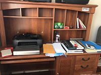 Wide shot showing Canon iP100 photo printer and assorted office supplies on wooden desk with shelves.