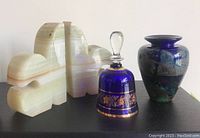 Photo of the full lot showing onyx bookends, cobalt blue glass vase, cobalt blue and clear glass bell with gold trim