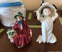 View of both Royal Doulton figurines side by side on a table showing relative size and details.