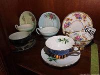 Five tea cups and saucers together showing variety of floral designs and colors