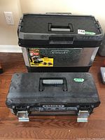 Two Stanley tool boxes stacked, the larger one behind smaller one, both with black textured lids and Stanley branding visible.