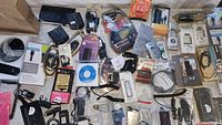 Wide view of an assortment of electronic accessories including cables, adapters, headphones, and small gadgets, many still in packaging