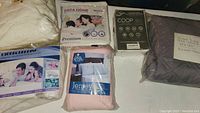 Full view of all bedding items laid out including packaged sheets, pillow, mattress and furniture protectors