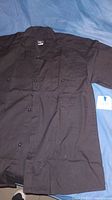 Full front view of one black button-up Jack Daniels shirt, size large tag visible beside it.