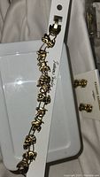 Gold-tone puppy charm bracelet on a display card showing multiple swinging puppy charms in playful poses.