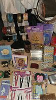 Full overview of the lot showing variety of stocking stuffer items including bracelets on display rack, scissors, tweezers, picture frames, and cases.