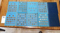 Photo shows blue coin collection cases for Lincoln Memorial Cents and Jefferson Nickels partially filled with coins on a wooden table.
