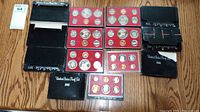 Overview of all five United States proof coin sets in their display cases on wooden surface.