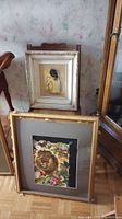 Two framed animal prints, one resting against the other, one with a lion print, the other with a tiger print, both matted and inside wooden frames with gold-tone beading detail.