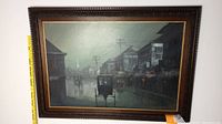 Framed painting depicting riverside buildings and a boat, measuring 43 by 31 inches with visible texture on the surface.