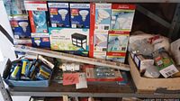 Full view of lightbulbs in boxes including Sunbeam LED flood lights and other types, plus blue container with assorted batteries and loose bulbs
