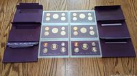 Photo showing two United States Mint Proof Set folders containing coins from the years 1992 and 1993 displayed open on a wooden surface.