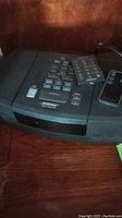 Bose Wave Radio/CD player on a wooden surface, with remote controls placed on top.