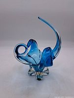 Front view of blue art glass elephant figurine showing curled trunk, legs and tail.
