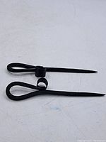 Pair of hand-forged iron hairpins displayed on white surface to show full length and design details