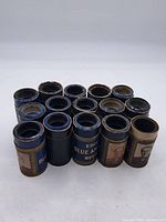 View of all 13 Edison Blue Amberol cylinders arranged in a group showing top and sides of containers.