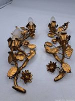 Pair of vintage gilt metal floral wall lights with multiple leaves and flowers, laying flat showing overall condition and design
