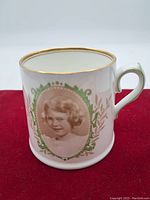 Side view of mug featuring portrait of young Princess Elizabeth of York with green laurel wreath and gold trim on rim and handle.