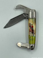 Photo showing the pocket tool open with a blade and a bottle opener extended, featuring a painted RCMP officer on horseback on the handle.