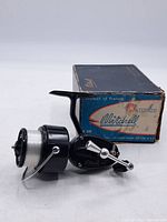 Side view of the Mitchell 300 fishing reel with original box behind it, showing overall condition and branding on box.