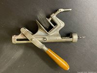 Full view of the mechanical corkscrew showing metal body and wooden handle with screw mechanism extended.