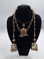 Front view of the two vintage necklaces displayed on a black bust. Both have red coral bead accents and silver bell-shaped pendants.
