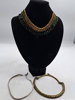 Full view of the three vintage necklaces displayed on a black mannequin bust and flat, showing the different sizes and styles