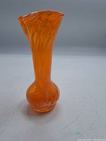 Full view of the orange glass vase showing its flared top and bulbous base with swirling patterns inside the glass.