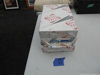 Three unopened packages of legal printer paper stacked, two white and one yellow, branded Victory Paper.