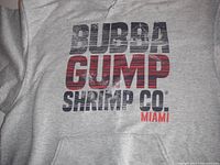Close-up photo of the front logo print on the gray hoodie showing 'BUBBA GUMP SHRIMP CO. MIAMI' text in distressed black and red ink.