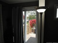 Floor lamp showing the top section with frosted glass shade and dark metal pole set against dark walls and window background.