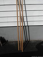 Three long narrow wood trim pieces leaning against a wall, straight grain visible, likely oak.
