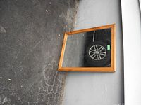 Full view of rectangular mirror with pine wood frame placed on the ground against a wall, showing the frame color and condition.