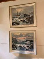 Two framed paintings of lighthouse and seascape with birds, ocean waves and rocky coastline, light-colored frames