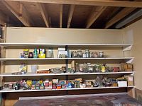 Wide view of shelves containing jars, boxes of nails and screws, small hardware packages, and containers of chemicals.