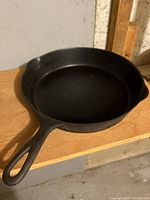 Top view of one cast iron frying pan with handle, showing black cooking surface and well-used condition.