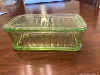 Side and top angled view showing ribbed details on the rectangular green depression glass refrigerator dish and its matching lid.