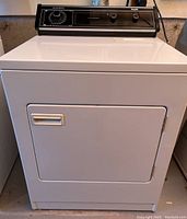 Front view of Inglis dryer showing white metal exterior and front-loading door with handle.