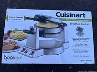 Cuisinart branded box showing front of the Belgian waffle and omelette maker baking a waffle and an omelette simultaneously. Shows BPA free, model number WAF-600C, and features such as 3-year warranty, 2 LED lights, audio beeps, and 180 degree rotation.