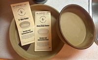 Photo showing both Pampered Chef 8-inch Mini-Baker and Deep Dish Baker ceramic dishes along with their recipe and instruction booklets.