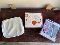 Photo of the boxed Clarisonic Pedi set, Philips Bikini Trimmer in packaging, and Serious Skincare case on wooden surface.