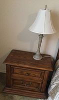 Full side view of wooden bedside table with lamp on top.