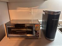 GE toaster oven beside Keurig coffee maker on a counter under wall outlets